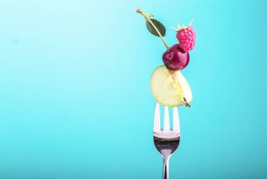 Sağlıklı beslenme, diyet ve antioksidan için mavi arka plan kavramına karşı meyveler ve gümüş çatal.