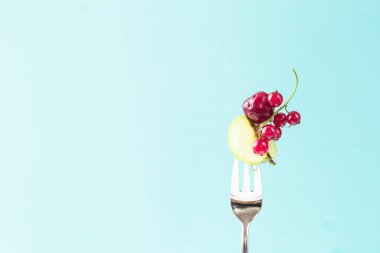 Uzayı metin için kopyala. Sağlıklı beslenme, diyet ve antioksidan için mavi arka plan kavramına karşı gümüş çatallı vişne üzümü. Yaz, şablon Uçan kiraz kırmızısı yükselme