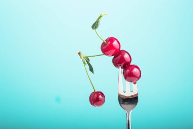 Sağlıklı beslenme, diyet ve antioksidan için mavi arka plan kavramına karşı meyveler ve gümüş çatal.