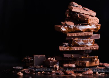 Çeşit çeşit çikolatalı şekerler. Çikolatalı şekerler. Koyu kahverengi arkaplan üzerinde Candy Design. Çeşitli çikolatalar. Şekerlemeci