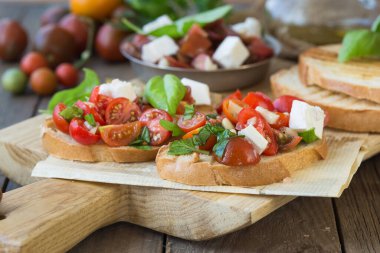 Domates, mozzarella peyniri ve fesleğen dilimleme tahtasında. Geleneksel İtalyan aperatifi veya aperatifi, antipasto.