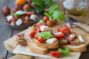 Domates, mozzarella peyniri ve fesleğen dilimleme tahtasında. Geleneksel İtalyan aperatifi veya aperatifi, antipasto.