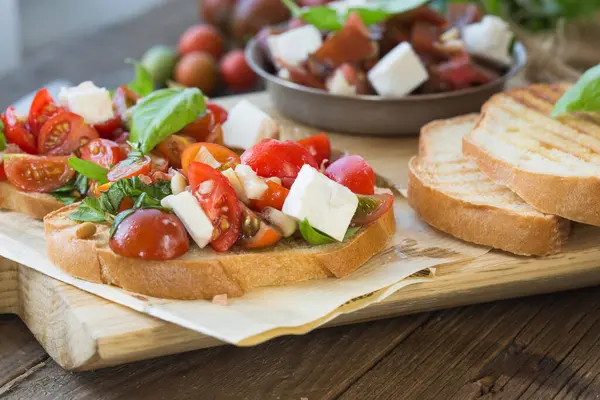 Domates, mozzarella peyniri ve fesleğen dilimleme tahtasında. Geleneksel İtalyan aperatifi veya aperatifi, antipasto.