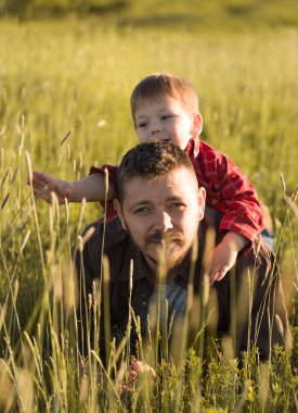 Küçük oğluyla dışarıda eğlenen mutlu genç bir baba. Aile hayatında mutluluk ve uyum..