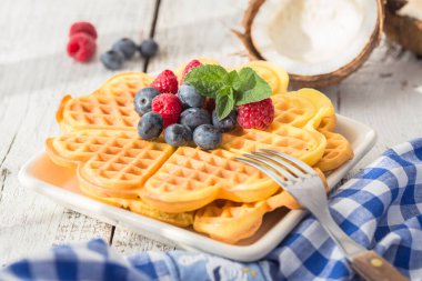 Krema ve taze böğürtlenli gofretler beyaz arka planda çikolata serpiştirilir. Üst görünüm, boşluğu kopyala. Ev yapımı Belçika Waffle 'ları