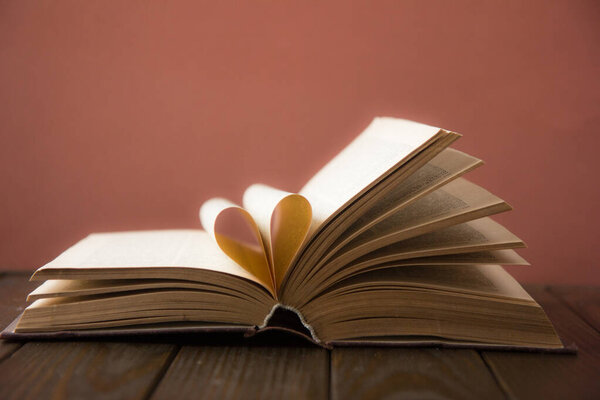 Old open hardback book, page decorate into a heart shape for love in Valentine`s. love with open book heart.