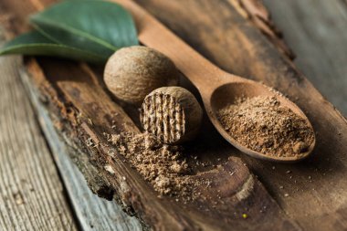 Tahta kaşık, yeşil otlar ve eski ahşap arka planda baharatlar.