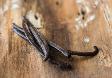 Kurutulmuş vanilya kabukları ve orkide vanilya çiçekleri ahşap arka planda