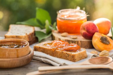 Kayısı reçeli ve ahşap masada taze kayısılar.