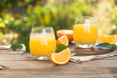 Bir bardak taze portakal suyu, olgun portakal suyu ve kırsal ahşap masada dilimler. Taze sıkılmış portakal suyu.