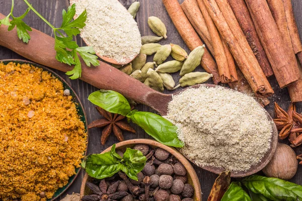 Ahşap arka planda çeşitli zemin baharatları var. Gürcü baharatları, Hint baharatları, Arap baharatları. Baharat çeşitliliği. Bitkiler ve baharatlar. Katman, siyah.