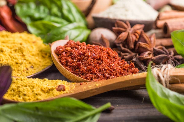 Ahşap arka planda çeşitli zemin baharatları var. Gürcü baharatları, Hint baharatları, Arap baharatları. Baharat çeşitliliği. Bitkiler ve baharatlar. Katman, siyah.