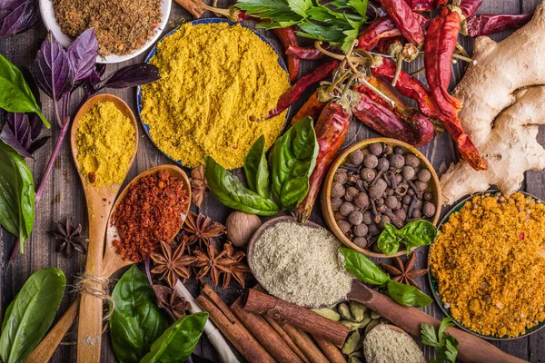 Ahşap arka planda çeşitli zemin baharatları var. Gürcü baharatları, Hint baharatları, Arap baharatları. Baharat çeşitliliği. Bitkiler ve baharatlar. Katman, siyah.