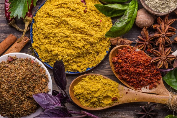 Ahşap arka planda çeşitli zemin baharatları var. Gürcü baharatları, Hint baharatları, Arap baharatları. Baharat çeşitliliği. Bitkiler ve baharatlar. Katman, siyah.