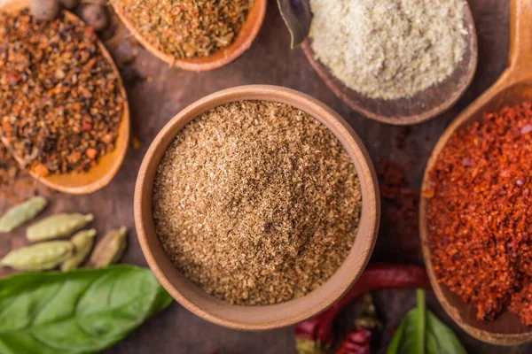 Ahşap arka planda çeşitli zemin baharatları var. Gürcü baharatları, Hint baharatları, Arap baharatları. Baharat çeşitliliği. Bitkiler ve baharatlar. Katman, siyah.