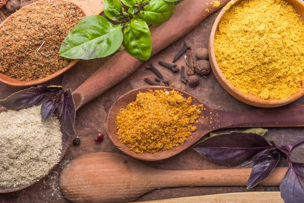 Ahşap arka planda çeşitli zemin baharatları var. Gürcü baharatları, Hint baharatları, Arap baharatları. Baharat çeşitliliği. Bitkiler ve baharatlar. Katman, siyah.