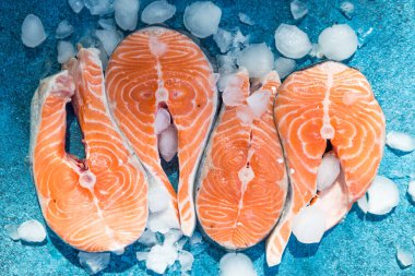 Somon balığı. Çiğ alabalık, kırmızı balık bifteği, yeşillik, limon ve zeytinyağı ile servis edilir. Somon pişirmek, deniz ürünleri. Sağlıklı yeme kavramı.