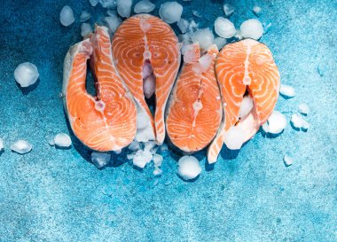 Somon balığı. Çiğ alabalık, kırmızı balık bifteği, yeşillik, limon ve zeytinyağı ile servis edilir. Somon pişirmek, deniz ürünleri. Sağlıklı yeme kavramı.