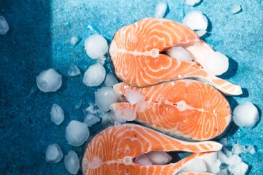 Somon balığı. Çiğ alabalık, kırmızı balık bifteği, yeşillik, limon ve zeytinyağı ile servis edilir. Somon pişirmek, deniz ürünleri. Sağlıklı yeme kavramı.