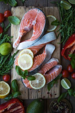 Somon balığı. Çiğ alabalık, kırmızı balık bifteği, yeşillik, limon ve zeytinyağı ile servis edilir. Somon pişirmek, deniz ürünleri. Sağlıklı yeme kavramı.