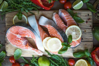 Somon balığı. Çiğ alabalık, kırmızı balık bifteği, yeşillik, limon ve zeytinyağı ile servis edilir. Somon pişirmek, deniz ürünleri. Sağlıklı yeme kavramı.