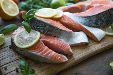 Somon balığı. Çiğ alabalık, kırmızı balık bifteği, yeşillik, limon ve zeytinyağı ile servis edilir. Somon pişirmek, deniz ürünleri. Sağlıklı yeme kavramı.