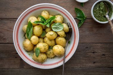 Lezzetli Young, fesleğenli haşlanmış patatesleri beyaz kasede, ahşap masa üzerinde pesto çorbası ile birlikte.