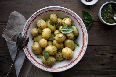 Lezzetli Young, fesleğenli haşlanmış patatesleri beyaz kasede, ahşap masa üzerinde pesto çorbası ile birlikte.