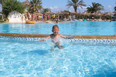 Küçük çocuk tatil köyünde havuzda eğleniyor, seyahat konsepti. 