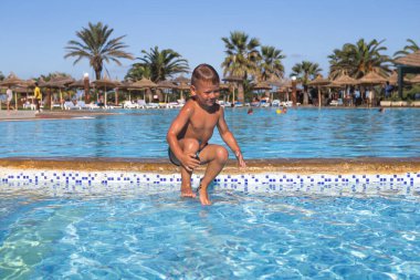 Küçük çocuk tatil köyünde havuzda eğleniyor, seyahat konsepti. 