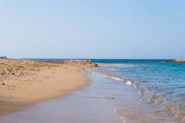 Temiz mavi suyu, altın kumu, renkli tekneleri ve arka planda dağları olan güzel bir sahil manzarası. Yunanistan ve İyon Denizi 'nin yaz manzarası.