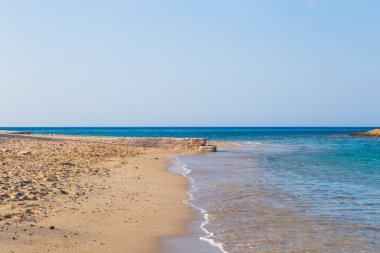 Temiz mavi suyu, altın kumu, renkli tekneleri ve arka planda dağları olan güzel bir sahil manzarası. Yunanistan ve İyon Denizi 'nin yaz manzarası.