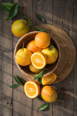 Masadaki ahşap kasede olgun portakalların üst görüntüsü.