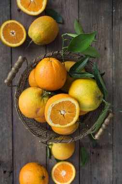 Masadaki ahşap kasede olgun portakalların üst görüntüsü.