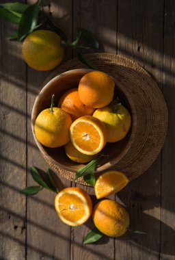 Masadaki ahşap kasede olgun portakalların üst görüntüsü.