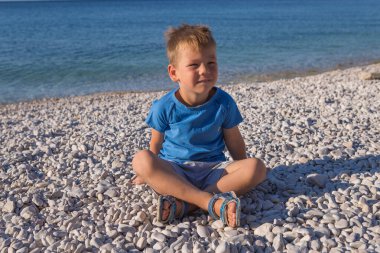 funny little boy jumping high on beach near sea shore in summer 