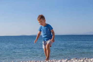 funny little boy jumping high on beach near sea shore in summer 