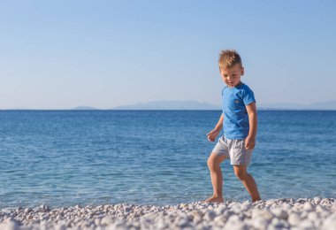 funny little boy jumping high on beach near sea shore in summer 