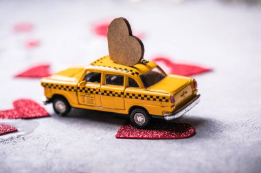 Kırmızı arka planda kırmızı kalp, sarı oyuncak taksi vagonunda. Kopyalama alanı olan seyahat aşkı kavramı.