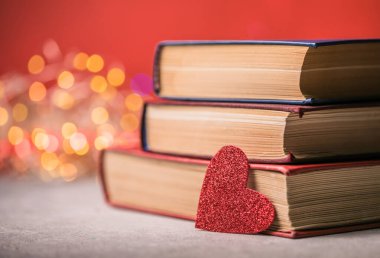 Bir yığın kitap ve kırmızı kalp. Romantik bir geçmişi var.