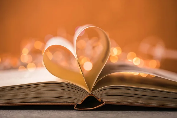 Book with love symbol on red background, heart shape from paper book.