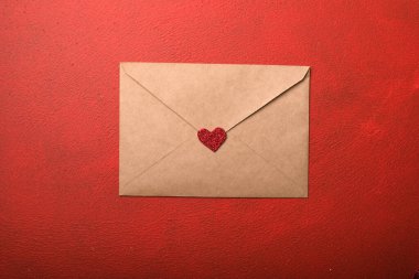 Kırmızı arka planda sevgililer günü kalpleri olan kağıt bir zarf. Düz yerde, üst tarafta. Sevgililer Günü konsepti için romantik aşk mektubu.