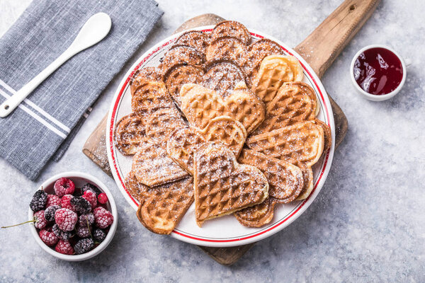 Freshly baked homemade heart shaped Belgium waffles  on gray background. European baked pastry sweets.  St. Valentine's Day breakfast concept.