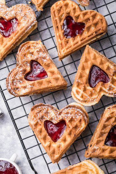 Freshly baked homemade heart shaped Belgium waffles  on gray background. European baked pastry sweets.  St. Valentine's Day breakfast concept.