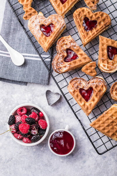 Freshly baked homemade heart shaped Belgium waffles  on gray background. European baked pastry sweets.  St. Valentine's Day breakfast concept.
