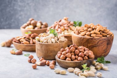 Gri arka planda, ahşap kaselerde fındık çeşitleri. Fındık, fıstık, badem, fındık, kaju.