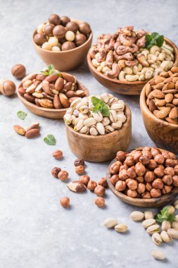 Gri arka planda, ahşap kaselerde fındık çeşitleri. Fındık, fıstık, badem, fındık, kaju.