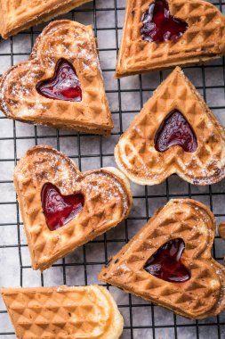 Gri arka planda taze pişmiş ev yapımı kalp şeklinde Belçika waffleları. Avrupa usulü hamur tatlısı. Sevgililer Günü kahvaltı konsepti.