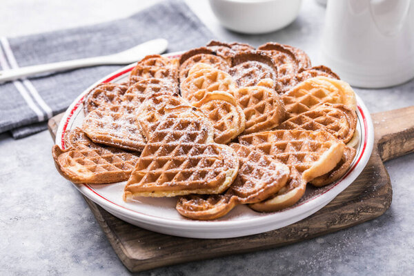 Freshly baked homemade heart shaped Belgium waffles  on gray background. European baked pastry sweets.  St. Valentine's Day breakfast concept.
