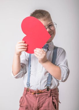 Beş yaşındaki gülümseyen çocuk aşkın, ailenin ve umudun kırmızı kalp sembolünü taşıyor. Sevgililer Günü 'nde kart geçmişi ya da aile ve çocukların korunmasıyla ilgili sosyal afişler.